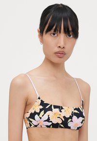 Blomster-bikinitopp med tynne rosa stropper, med en svart bakgrunn prydet med pastellfargede blomster og et glatt, elastisk stoff.