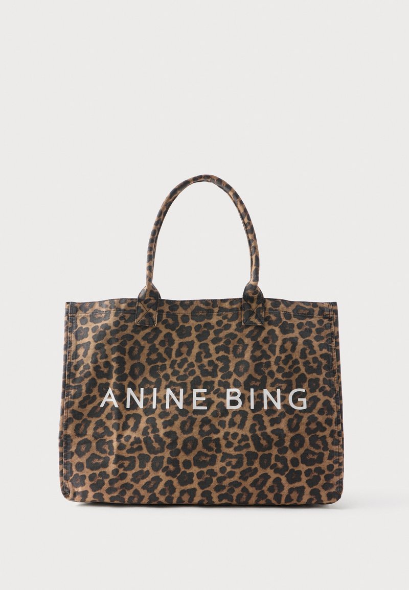 Bolso grande tipo tote con estampado de leopardo en marrón y negro y texto blanco "ANINE BING" en el frente, con dos asas.