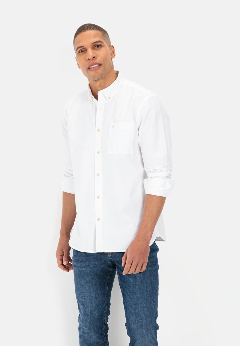Witte knoopshirt met lange mouwen en een borstzak, gemaakt van een lichtgewicht stof. Vergezeld van blauwe denim jeans.