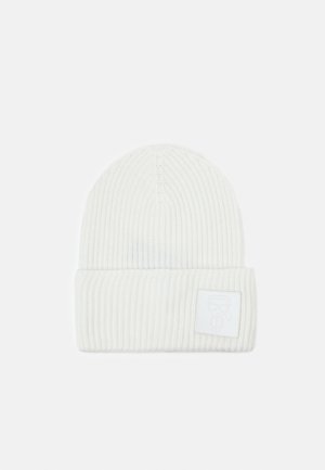 Bonnet blanc en maille côtelée avec revers plié et petite écusson carré affichant un logo figure minimaliste à l'avant.