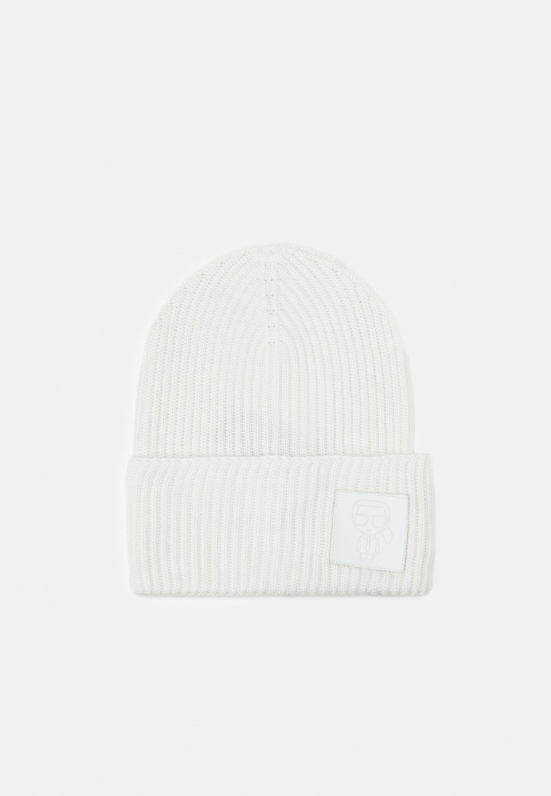 Bonnet blanc en maille côtelée avec revers plié et petite écusson carré affichant un logo figure minimaliste à l'avant.