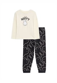 Twee-delige pyjama set bestaande uit een crèmekleurige long sleeve top met een Miffy graphic en zwarte broek met een wit konijnenpatroon. Zacht katoen.