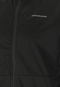 Svart isolerad jacka med dragkedja fram. Har "ENDURANCE"-logotyp, slät textur och en åtsittande design. Idealisk för kalla väderförhållanden.