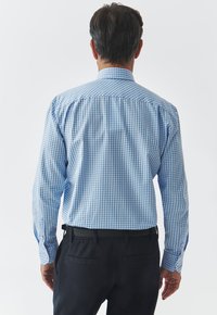 Camisa de manga larga en un patrón de cuadros azul y blanco, con cuello y puños abotonados, confeccionada en una ligera tela de algodón.