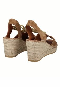 Sandalias de cuña de ante marrón con tacón de yute trenzado. Diseño de pestaña abierta con tiras entrelazadas y una suela texturizada para mayor agarre.