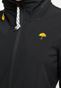 Black jacket featuring a high collar, front zipper, and a small yellow umbrella embroidered on the chest. Textured, water-resistant material.