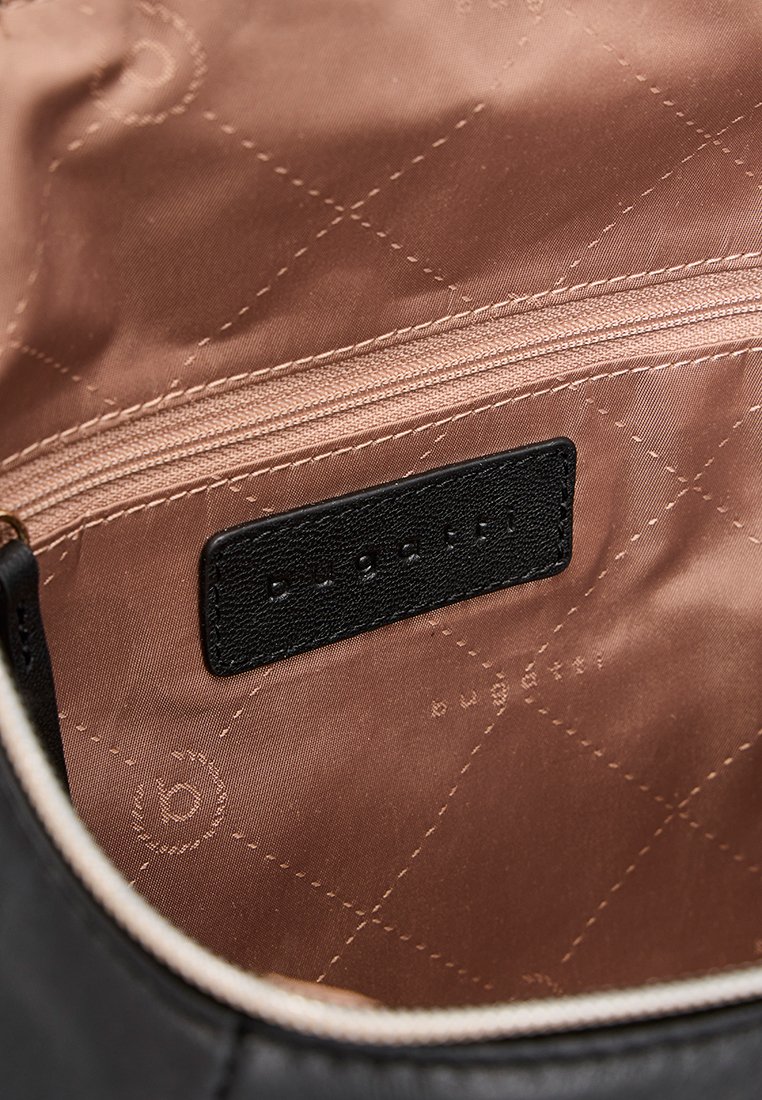 Intérieur d'un sac à main en cuir noir avec un revêtement matelassé marron, comportant une poche zippée et une étiquette noire en relief.