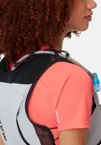 Hydrationsrucksack in Grau und Schwarz mit Netz-Akzenten, ausgestattet mit einem durchsichtigen Trinkschlauch mit blauer Düse, getragen über einem leuchtend pinken Shirt.