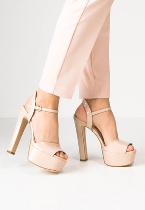 Beige patent high-heeled platform sandals with an open toe, ankle strap, and block heel design, showcasing a glossy texture.