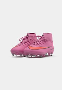 Roze voetbalschoenen met een textuur bovenwerk, voorzien van een zwart en oranje Nike swoosh, hoog model en metalen studs op de zool.