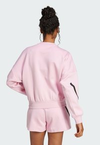 Pink sweatshirt with a textured surface, ribbed cuffs, and a waistband, paired with matching shorts. Features black accents on the sleeves.