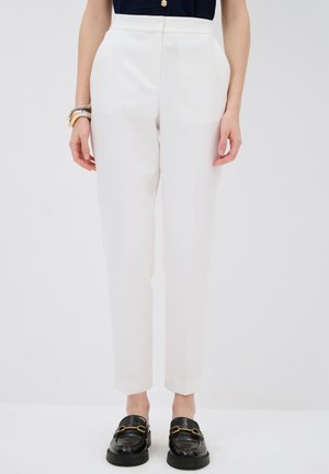 White tailored trousers with a high waist, straight-leg design, and smooth texture. Paired with black loafers featuring gold accents.