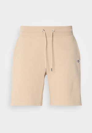 Beige cotton shorts with an elastic waistband, adjustable drawstring, and side pockets. Features a small logo on the left thigh.