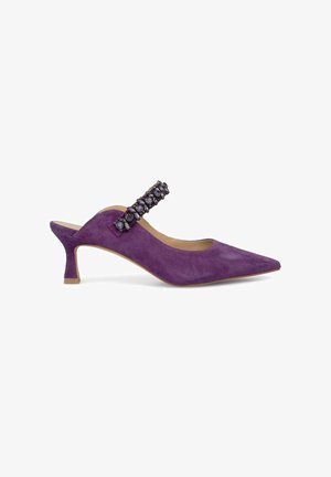 Scarpa slingback in suede viola con punta appuntita e una cintura decorativa con gemme viola, poggiata su un tacco basso.