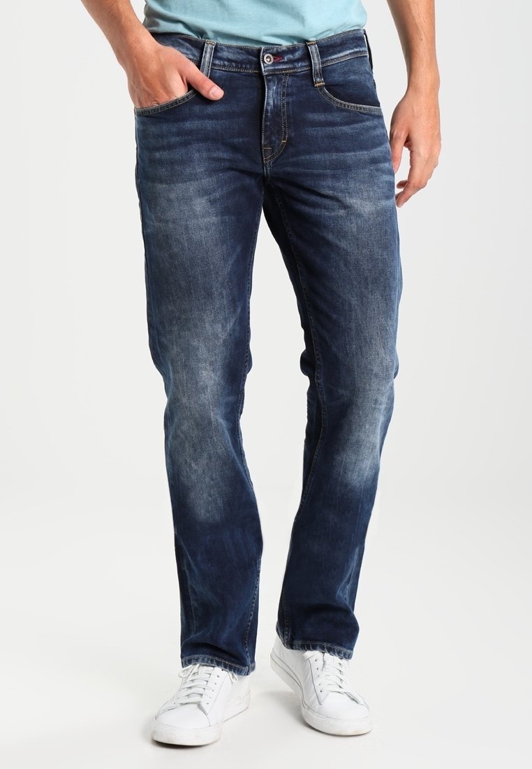 Tmavě modré džíny se sepranou texturou, rovného střihu, pěti kapsami a zipem. V kombinaci s bílými teniskami.