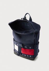 Σακίδιο πλάτης από ύφασμα ναυτικού μπλε με φερμουάρ στην κορυφή, που διαθέτει αντίθετο κόκκινο και λευκό κάτω πάνελ και διακριτικά με λογότυπο στη βάση.