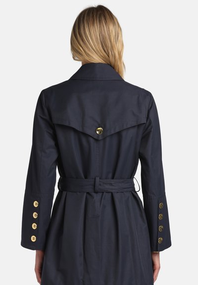 Palton trench bleumarin cu talie cu curea, nasturi aurii pe maneci și detaliu cu deschizătură la spate. Material neted, croială până la genunchi.