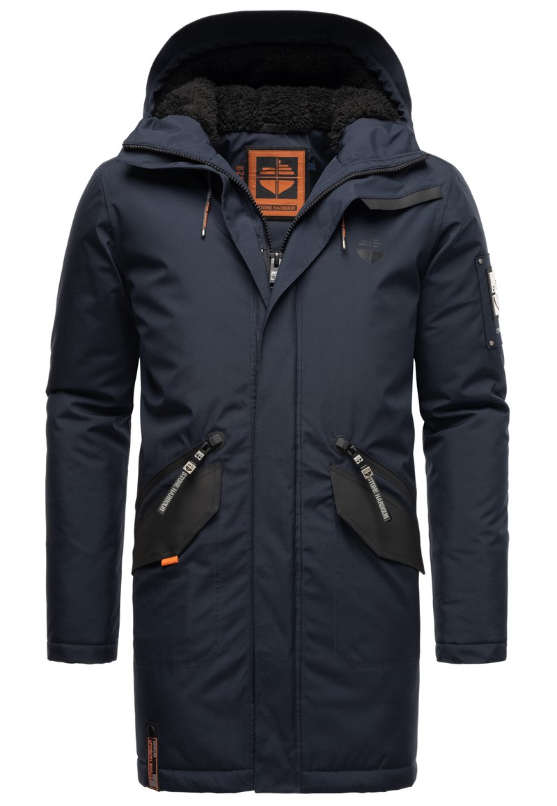 Mörkblå parka med en texturerad huva, dragkedja fram och två framfickor med svarta detaljer och orange accenter.