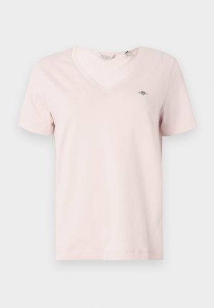 T-shirt rosa de decote em V feita de algodão macio com mangas curtas. Apresenta um pequeno logótipo no peito esquerdo e um ajuste padrão. Textura suave.