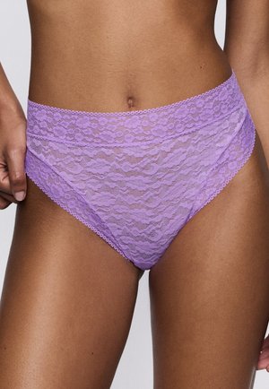 Gros plan d'une personne portant des sous-vêtements en dentelle lavande taille haute avec motif floral sur peau nue.