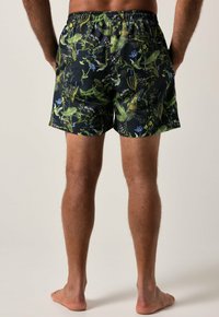 Pantaloni da nuoto con base nera e vivaci motivi floreali verdi e blu, vita elastica e vestibilità comoda. Tessuto morbido.