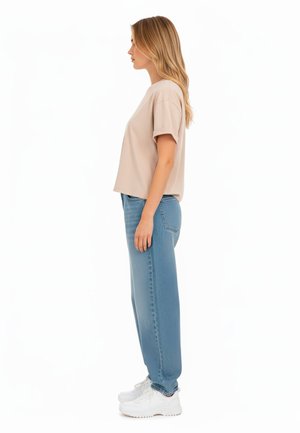 Beige short-sleeve top with a relaxed fit, paired with light blue high-waisted straight-leg jeans and white sneakers.