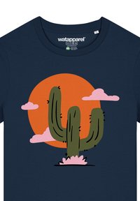 Marine T-shirt met een cactustekening in het groen, tegen een oranje cirkel met roze wolken, gevormd met eenvoudige lijnen.