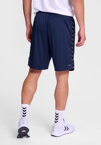 Pantalones cortos deportivos navy con una textura suave y lisa y acentos en forma de chevrón negros en los lados. Cintura elástica para mayor comodidad.
