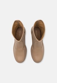 Bottines en cuir marron avec des panneaux élastiques sur les côtés, orteils ronds et finition lisse. Intérieur doublé de tissu beige.