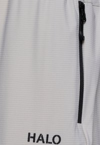 Close-up of light gray fabric with a black vertical zipper and black "HALO" text printed below the zipper.