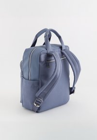 Mochila de tela azul con dos correas ajustables para los hombros, un asa superior, detalles en cremallera plateados y un bolsillo lateral para almacenamiento adicional.