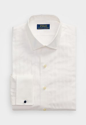 Chemise blanche avec un col pointu, des plis verticaux, des boutons jaunes et un poignet replié avec un accent marine. Étiquette Polo Ralph Lauren.