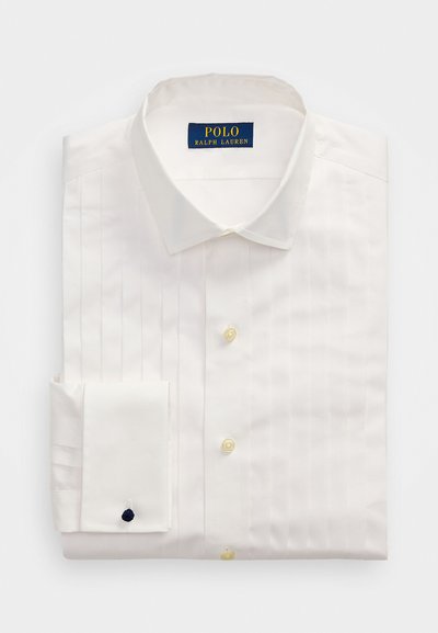 Camisa branca de vestir com colarinho pontudo, pregas verticais, botões amarelos e punho dobrado com um acento em azul-marinho. Etiqueta da Polo Ralph Lauren.