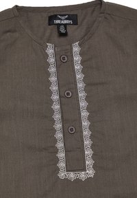 Braunes Shirt mit rundem Halsausschnitt, vorderem Knopfverschluss und aufwendiger weißer Stickerei entlang der Knopfleiste. Verfügt über braune Knöpfe.
