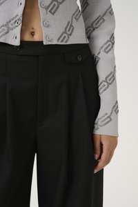 Grey ribbed cardigan with chain pattern and rhinestones, paired with high-waisted black pleated trousers featuring button details.