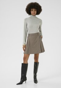 Šedý rolák spárovaný s hnědými kostkovanými skater sukněmi a vysokými černými stiletto botami, s přiléhavým střihem a kapsami.