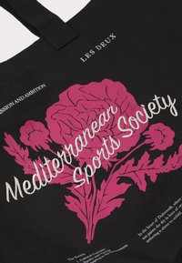 Juodas rankinis krepšys su dideliu rožiniu rožės piešiniu ir žaliais lapais, balta siuvinėta tekstu "Mediterranean Sports Society" ir ženklinimu viršuje.