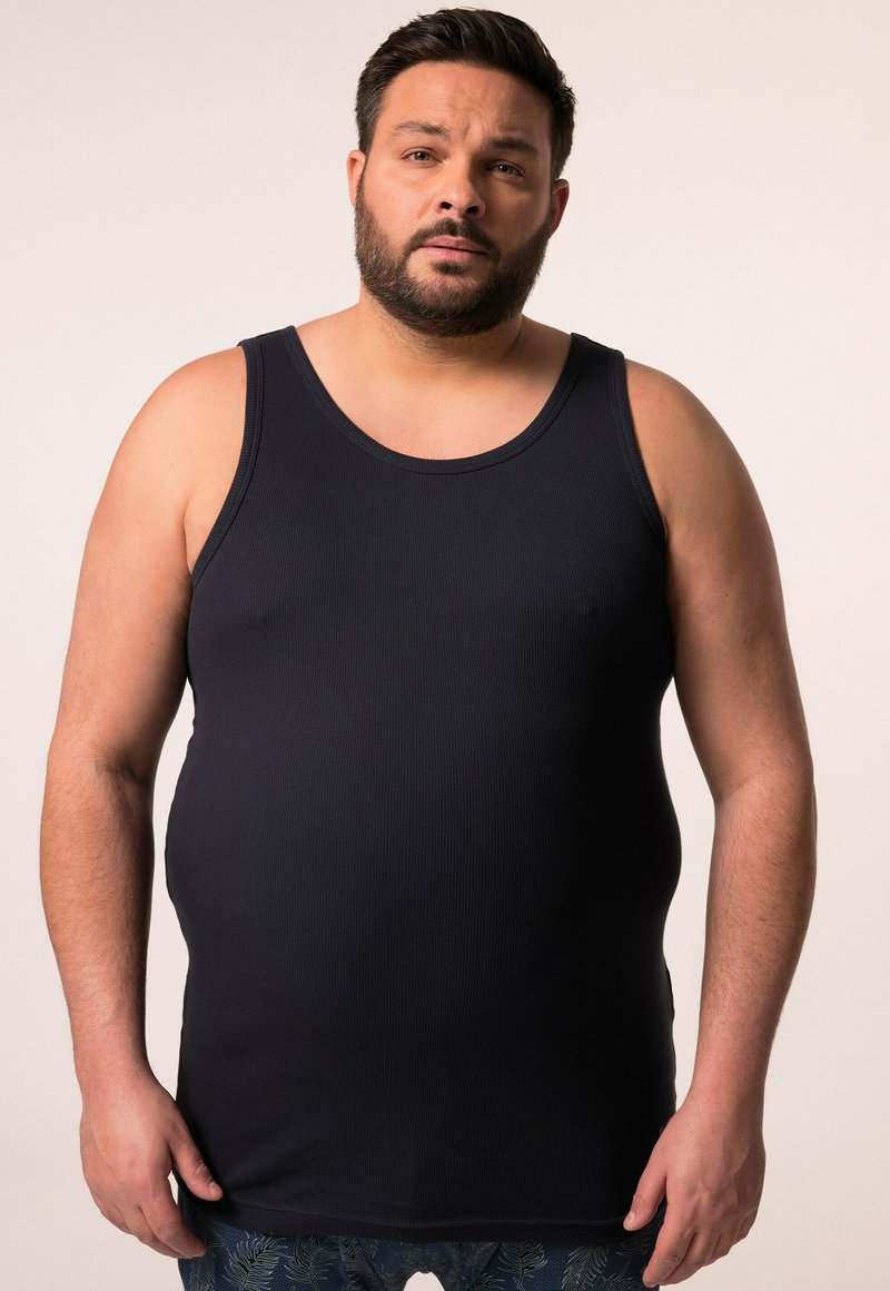 Navy blue ribbed tank top with wide straps and a crew neck, fitted shape, and soft texture, worn by a man against a neutral background.
