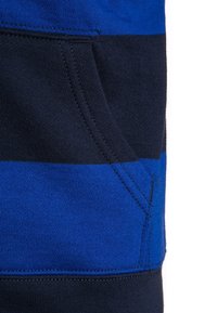 Blå och svart randig tyg med en ficka, mjuk textur och synliga sömmar längs kanterna.