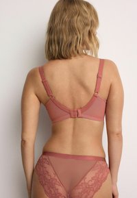 Roosa rinnahoidja ja sobivad pitsäärega püksikud; sile materjal; reguleeritavad rihmad; tagaküljel konksu ja silma kinnitussüsteem; lillelised pitsdetailid.