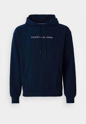 Tummansininen huppari, jossa on etutasku, säädettävät nyörit ja "TOMMY HILFIGER" -logo valkoisella tekstillä rinnassa.