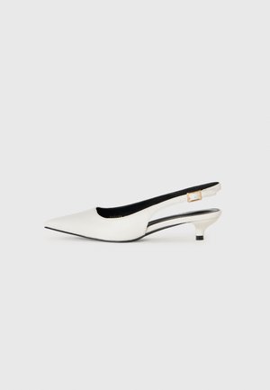 Hvite lær lavhæls slingback-sko med spiss tå og gullspenne på en enkel lys bakgrunn.