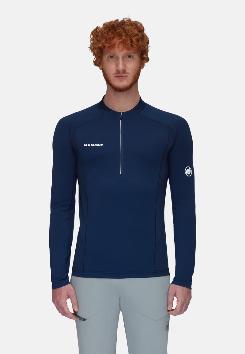 Marineblaue Langarm-Basisschicht-Shirt mit einem Viertel-Reißverschluss, kontrastierenden Nähten, Mammut-Logo auf der Brust und einem Emblem auf dem rechten Ärmel. Glatte Textur.