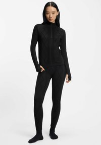 Czarny termiczny zestaw sportowy składający się z zapinanego na zamek bluzy z teksturowanym wzorem diamentu oraz dopasowanych legginsów z podobnym wzorem.