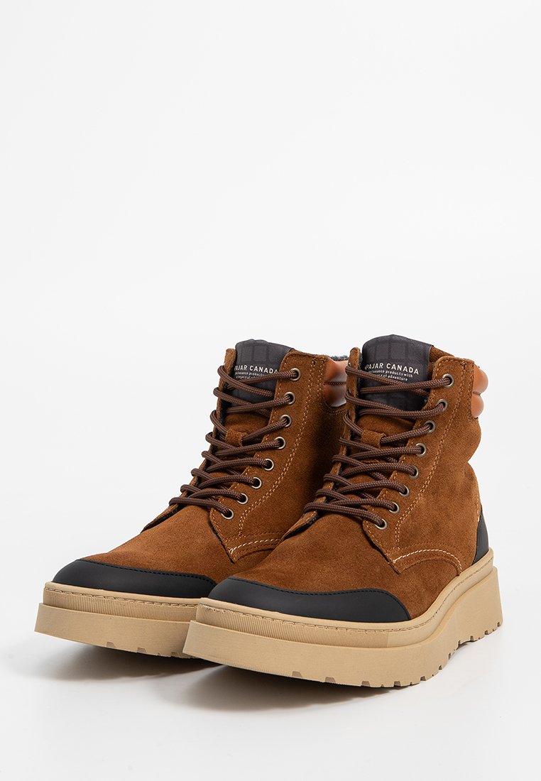 Braune Wildleder-Mid-Top-Stiefel mit dunklen Gummispitzen, braunen Schnürsenkeln, einer strukturierten tanfarbigen Sohle und einem erhöhten Rücken zur Unterstützung des Knöchels.