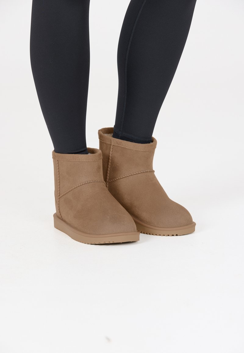 Bruna ankelhöga stövlar i mjukt mocka med texturerad yta, med rund tå och flexibel gummisula.