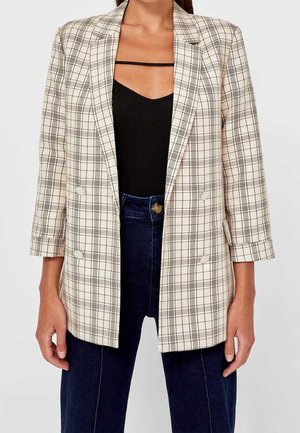 Blazer en plaid beige avec un motif à carreaux noir, design double boutonnage, revers en notch et manches trois-quarts. Tissu doux, sans embellissements visibles.