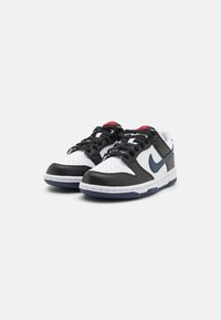 Nike Dunk sportbačiai su juodos odos ir baltos tekstilės viršumi, mėlynais akcentais, perforuota pirštų dėžute ir juodais raišteliais.