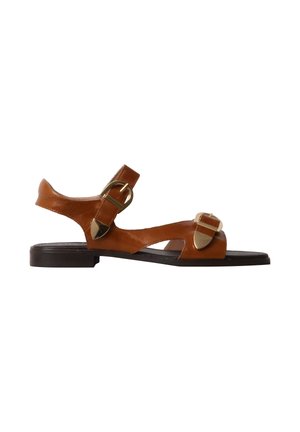 Sandale plate en cuir marron avec deux boucles dorées réglables et une semelle basse noire, présentée en profil latéral sur fond blanc.