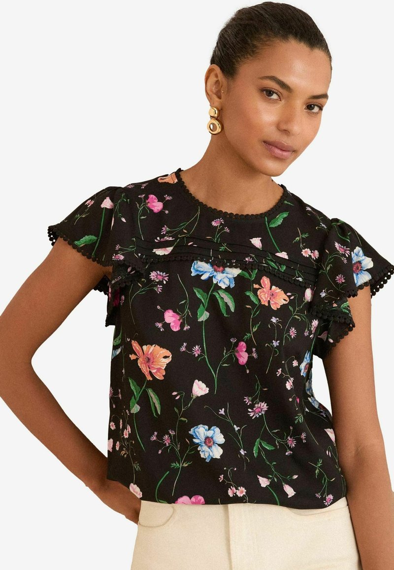 Blusa nera con maniche a sbuffo corte, caratterizzata da vivaci motivi floreali, bordo in pizzo sul colletto e tessuto leggero.